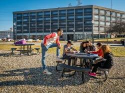 Students sitting around a table with Blanton Hall in the background and blue skies